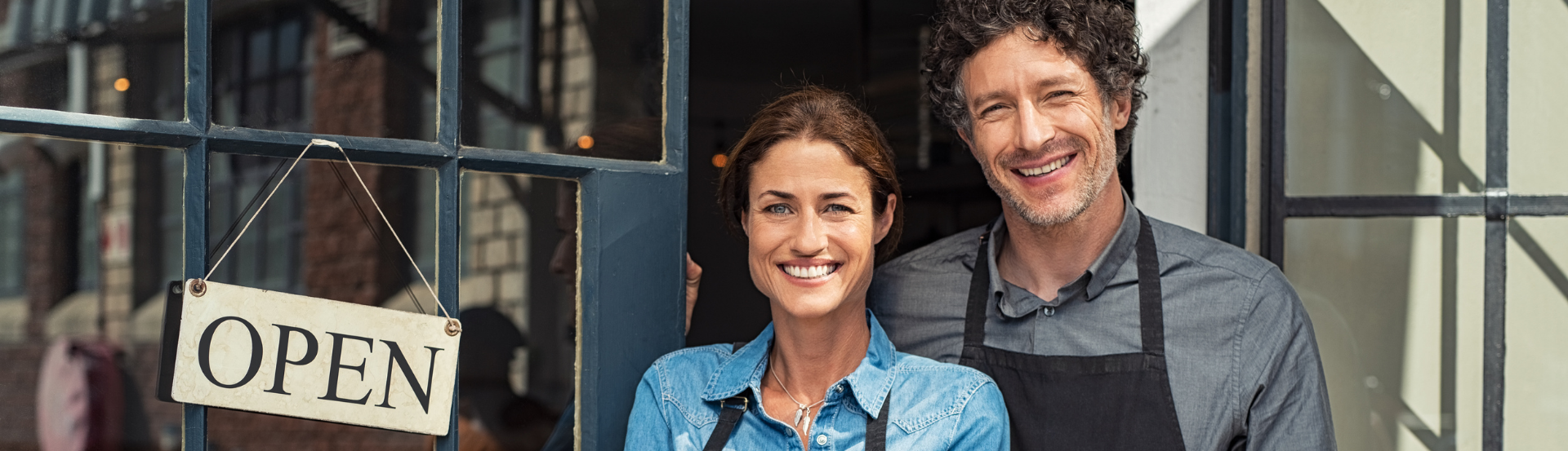 couple standing in front of an open sign at a storefront